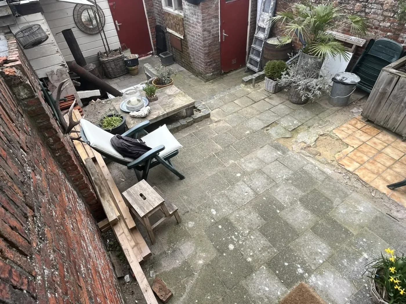 Mossige oude tegels in een achtertuin aan de Vuurtorenweg in Den Haag, vóór de renovatie